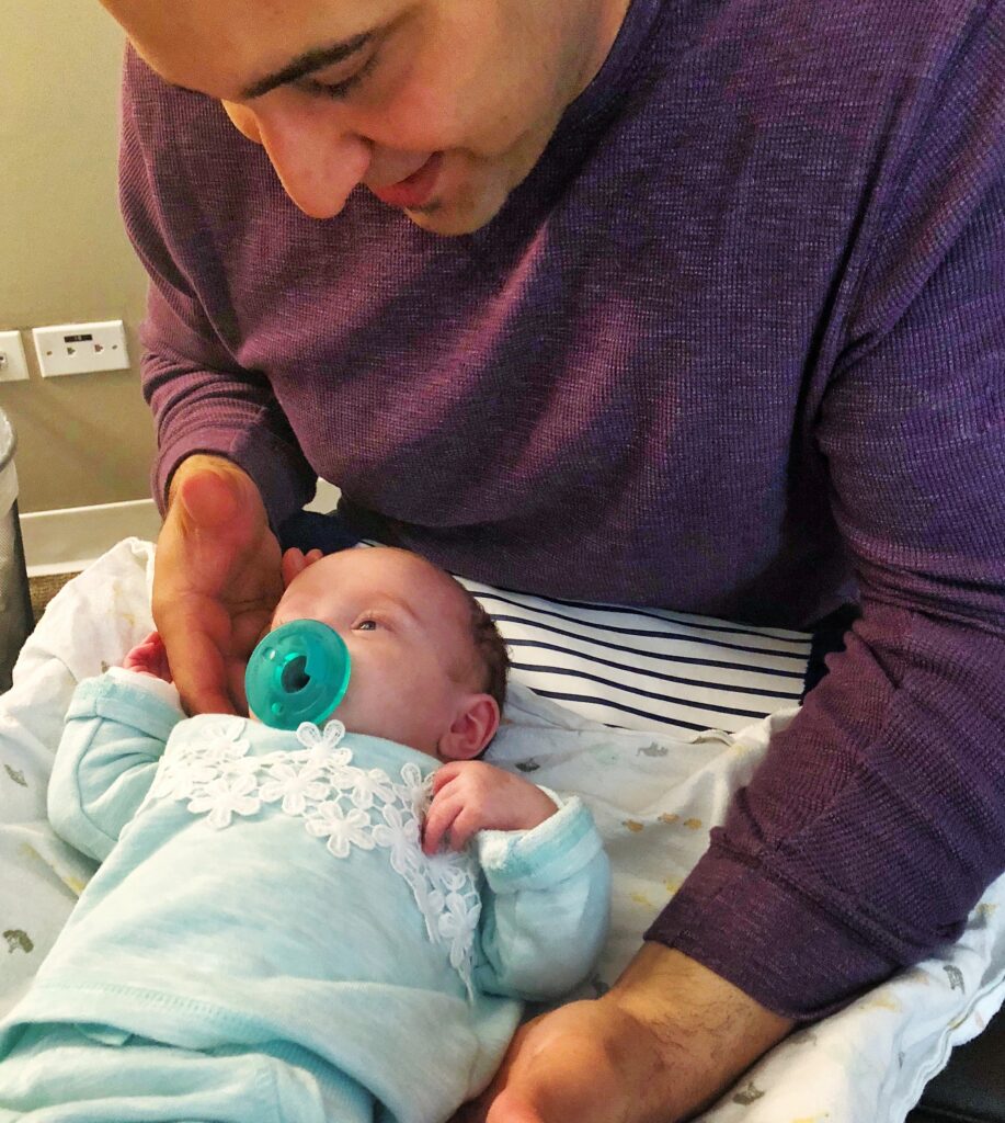 Pediatric chiropractor performing a gentle spinal adjustment on an infant in a calm clinical setting.